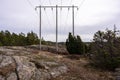 Spring landscape of the Swedish forest with evergreen trees and wild juniper. High voltage power line stretches across rocky hills