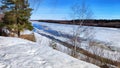 Spring landscape with tree with bare branches, river with ice, snow below on river and blue sky in the background in Royalty Free Stock Photo