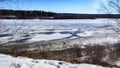 Spring landscape with tree with bare branches, river with ice, snow below on river and blue sky in the background in Royalty Free Stock Photo