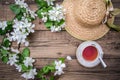 Spring layout with branches of a flowering apple tree, a cup of tea and a straw hat Royalty Free Stock Photo