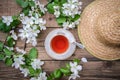 Spring layout with branches of a flowering apple tree, a cup of tea and a straw hat Royalty Free Stock Photo