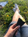 Spring meadow with green grass and yellow dandelions. One can see the legs of a girl who is resting, holding an ice cream in a Royalty Free Stock Photo