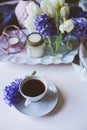 spring morning at home with cup of coffee, candles and flowers on white table