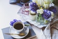 Spring morning at home with cup of coffee, candles and flowers on white table