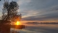 On a spring morning, the sun rises over the lake and illuminates the clouds. The sky and clouds are reflected in the calm water. R Royalty Free Stock Photo