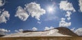 Spring in the mountains. Snow on the hillside and the sun on a blue sky with white clouds. Panoramic Royalty Free Stock Photo