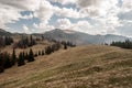 Spring mountais with mountain meadow, trees, hills with small snow fields and blue sky with clouds Royalty Free Stock Photo