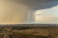 Spring natural and urban panoramic landscape with approaching huge storm cloud and heavy rain over burnt field and large city on Royalty Free Stock Photo