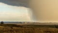 Spring natural and urban panoramic landscape with approaching huge storm cloud and heavy rain over burnt field and large city on Royalty Free Stock Photo