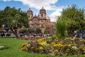 Spring photo at Cuzco main square called Plaza de Armas where you can see a beautiful cathedral behind and many colorful flowers a