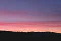 Spring pink and blue sunset over the forest. Pink and blue clouds at sunrise. Tender dawn paints over a dark forest silhouette. Royalty Free Stock Photo