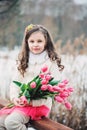Spring portrait of child girl with tulips bouquet on the walk