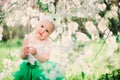 Spring portrait of cute baby girl in green skirt enjoying outdoor walk in blooming garden Royalty Free Stock Photo