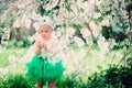 Spring portrait of cute baby girl in green skirt enjoying outdoor walk in blooming garden Royalty Free Stock Photo