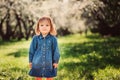 Spring portrait of cute little toddler girl in blue jeans dress walking in blooming park Royalty Free Stock Photo