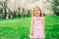 Spring portrait of cute little toddler girl in blue jeans dress walking in blooming park Royalty Free Stock Photo