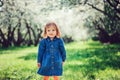 Spring portrait of cute little toddler girl in blue jeans dress walking in blooming park Royalty Free Stock Photo