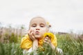 Spring portrait with  dandelions. Little girl with yellow scarf and a flower in her hair holds yellow dandelion in her hand. Royalty Free Stock Photo