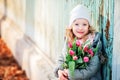 Spring portrait of happy child girl with tulips bouquet for woman's day