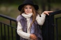 Spring portrait of a little girl.Sweet girl with big brown eyes in a black hat and a fur vest. Royalty Free Stock Photo