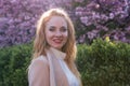 Spring portrait of red-haired beauty in blooming garden with cherry-tree. Young attractive woman with long curly hair in spring Royalty Free Stock Photo