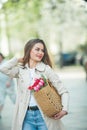 Spring portrait of a young beautiful happy woman 28 years old with long well-groomed hair holds a wicker bag in her hands with a Royalty Free Stock Photo