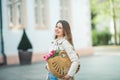 Spring portrait of a young beautiful happy woman 28 years old with long well-groomed hair holds a wicker bag in her hands with a Royalty Free Stock Photo