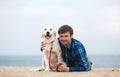 Spring portrait of a young man with a dog on the beach Royalty Free Stock Photo