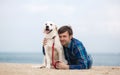 Spring portrait of a young man with a dog on the beach Royalty Free Stock Photo