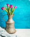 Spring purple tulips in vintage rustic copper jug, blue background