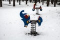 A spring riders - elephant and motorcycle - in playground at park covered with snow