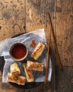 Spring rolls with chili sauce and chopsticks on a wooden background. Overhead view. Vietnamese Food.