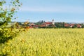 Spring rural landscape with green field, village and blue sky Royalty Free Stock Photo