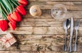 Spring rustic table setting with red tulip, glass and vintage cutlery on the wooden background Royalty Free Stock Photo