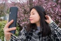 Spring sakura selfie - young happy and cute Asian Chinese tourist woman taking self portrait with mobile phone smiling cheerful in Royalty Free Stock Photo