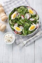 Spring salad with radish, cucumber, lettuce mix and eggs close-up in a plate. Vertical top view