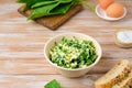 Spring salad of wild garlic and boiled eggs in a ceramic bowl on a wooden background. The use of wild plants for food, the first Royalty Free Stock Photo
