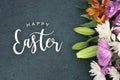 Happy Easter holiday script text over dark background texture and flowers Royalty Free Stock Photo