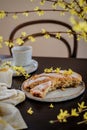 Spring setting with home baked apple pie and forsythia blooms on a dark table.