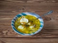 Spring soup with sorrel and boiled egg in a deep striped ceramic plate on a wooden background and with a tablespoon Royalty Free Stock Photo