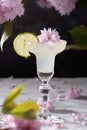 Spring still life with a glass of cold Margarita with lime, pink sakura flowers