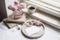 Spring still life scene. Greeting cards mockups, marble tray, cup of coffee, old books. Vintage feminine styled photo