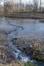 Spring stream flowing from drained muddy pond Royalty Free Stock Photo