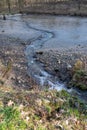 Spring stream flowing from drained muddy pond Royalty Free Stock Photo