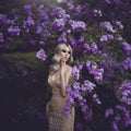 Spring style. Beautiful sensual girl blonde in spring. Blossoming spring garden. Young girl in a gold elegant dress Royalty Free Stock Photo