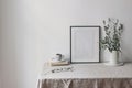 Spring, summer breakfast still life scene. Cup of coffee, books and empty black picture frame mockup. Beige linen