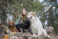 In the spring, on a sunny day, a girl with a ginger dog is playing on a log in the forest, and a Russian greyhound is standing Royalty Free Stock Photo