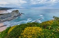 Spring sunset sea rocky coast landscape with small sandy beach  and yellow flowers in front. Arnia Beach, Spain, Atlantic Ocean Royalty Free Stock Photo