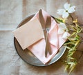 Spring Table Place Setting with dogwood flowers, light pink napkin, silverware and a blank card for menu or invitation.