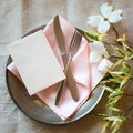 Spring Table Place Setting with dogwood flowers, light pink napkin, silverware and a vertical blank card for menu or invitation.